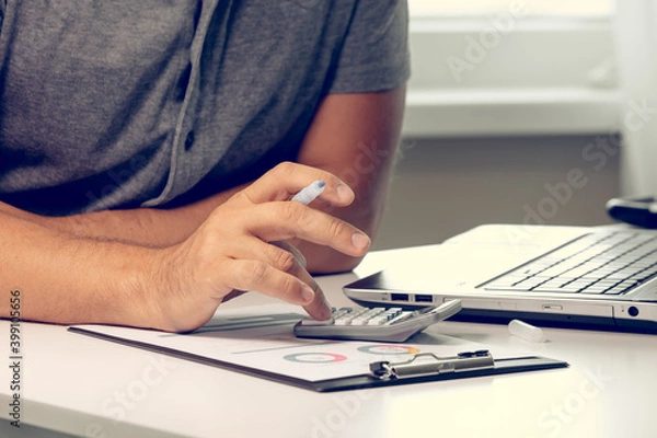 Fototapeta Businessman working with financial data hand using calculator and making calculations. Business financial and accounting concept.