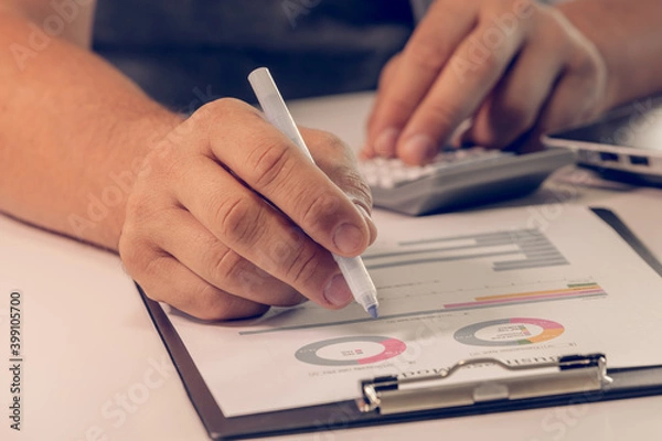 Fototapeta Close up of businessman hands working with finances using calculator on white desk in the office.