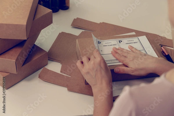 Fototapeta Close-up of woman hands at table with cardboard boxes