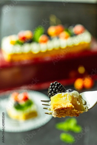 Fototapeta A blackberry on a piece of tasty lemon curd tart with whipped cream and fresh berries on the top. Close up. Vertical orientation.