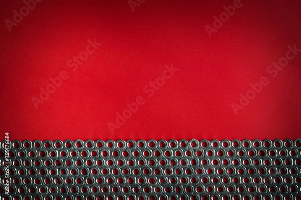 Obraz Pattern made of metal nuts on a bright red background. Copy space