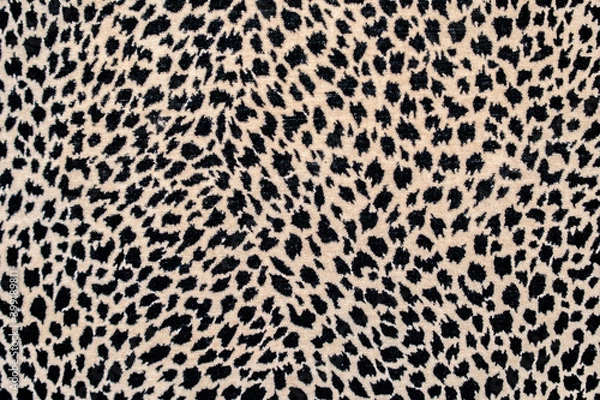Fototapeta Textured spotted background, repeating seamless pattern of black spots on a beige or yellow background: space for text, leopard skin pattern for fabric