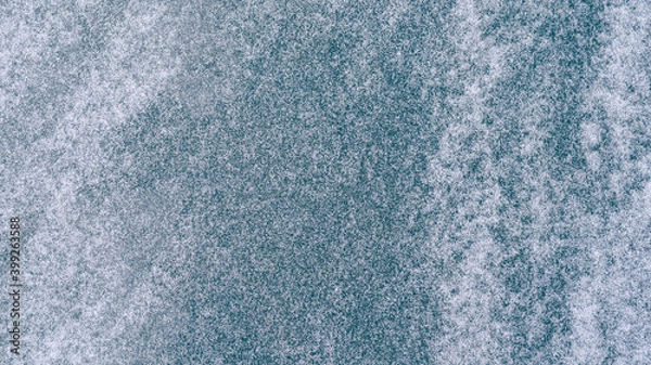 Fototapeta Top view flatlay photography of ice surface of frozen winter river and fresh white snow blowing by wind. Abstract natural winter background.