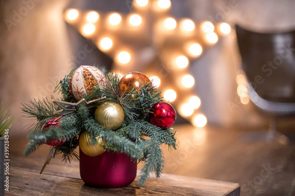 Fototapeta The New Year's little tree with Christmas toys at the table. Christmas tree and bokeh lights of the big star. Сhristmas ball and snowflake hanging on the tree. Decorated christmas tree.
