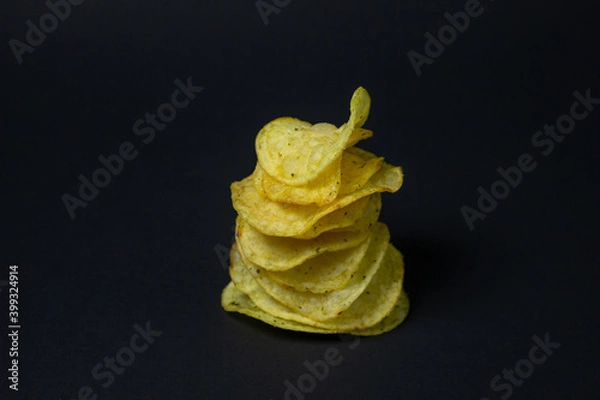 Fototapeta Chips on a black background. Unhealthy food. Crispy potato chips lay on top of each other