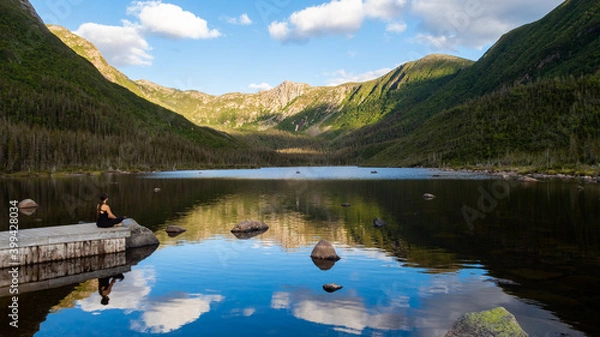 Obraz Young WOman sitting alone in front of the lake of the Americans, in the Gaspésie national park, Canada