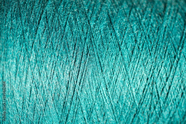 Fototapeta Background of a close up of aquamarine thread for sewing fabric: seamless pattern of twisted thread in a trendy color, soft focus, selective focus, space for text