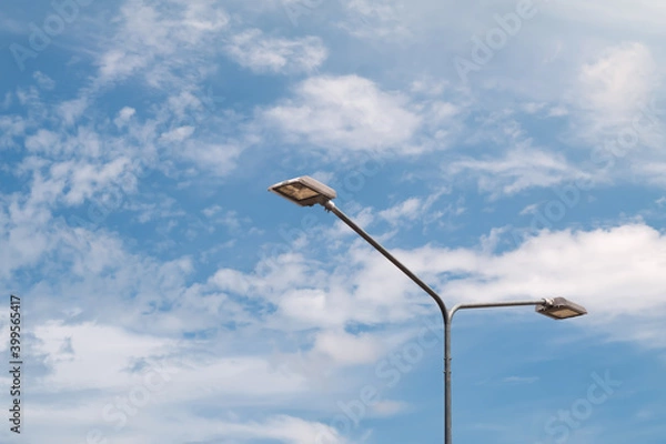 Fototapeta Streetlight with lamp pole against blue sky and clouds background.
