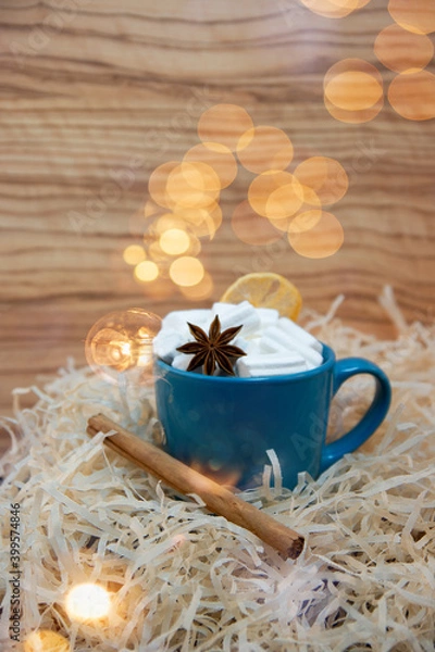 Fototapeta White marshmallow in a green mug with star anise and cinnamon, glare from sparkles, romantic blur.