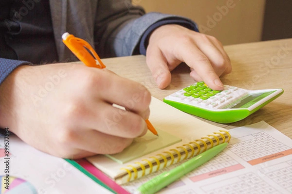 Fototapeta hand of young man using calculator for calculating family budget cost bills on desk in home office, plan money cost saving, investment, business finance, expenses