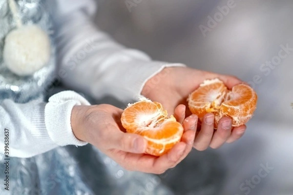 Fototapeta a woman's hands in a shiny suit hold a peeled tangerine