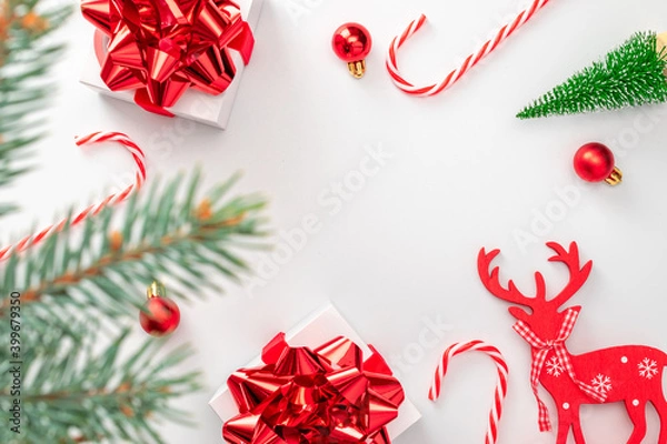 Fototapeta Winter banner. White gifts with scarlet bow, red balls and sparkling lights in xmas decoration on white background for greeting card. Flat lay, top view, copy space.