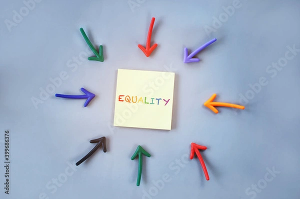 Fototapeta Top view of equality word on yellow sticky note with colorful arrow on grey background. Social issue concept and lgbt idea