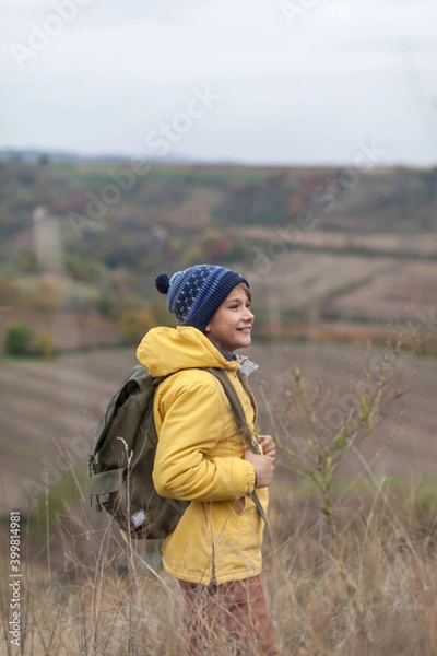 Fototapeta Happy little hiker walking through tall grass in autumn day on a hill.
