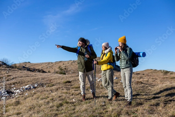 Fototapeta A group of friends is hiking at the top of the mountain and enjoying the fresh air. 