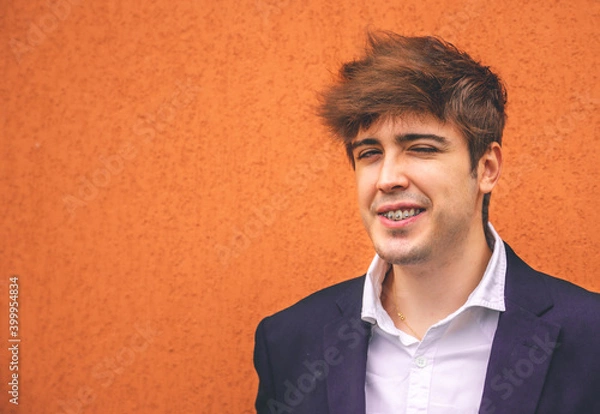 Fototapeta Guy in suit smiling on an orange wall.