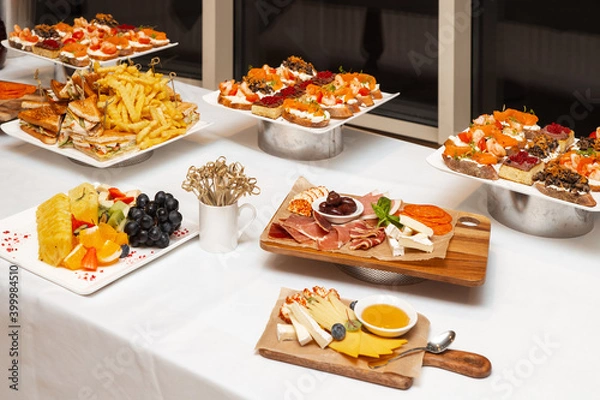 Fototapeta Сatering. Banquet table with different snacks and desserts