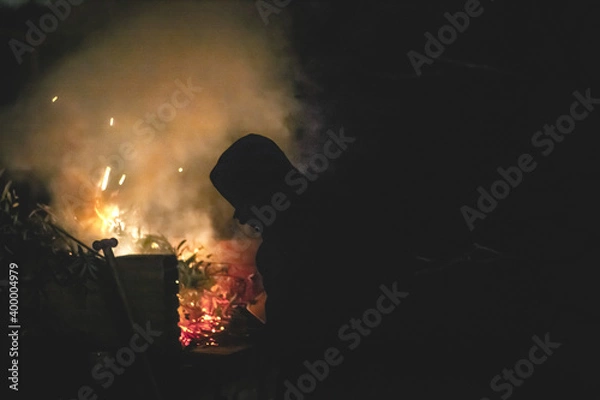 Obraz Silueta de una persona cerca de una hoguera de rastrojos en una construcción de ladrillo por la noche
