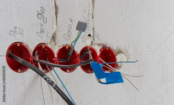 Obraz Installation of electrical wiring, red plastic boxes and electrical cables on the wall, repair concept