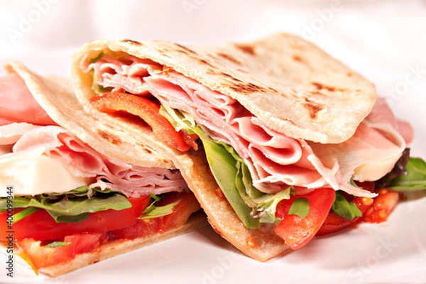 Fototapeta Traditional Italian piadina with ham, cheese, tomato and salad.