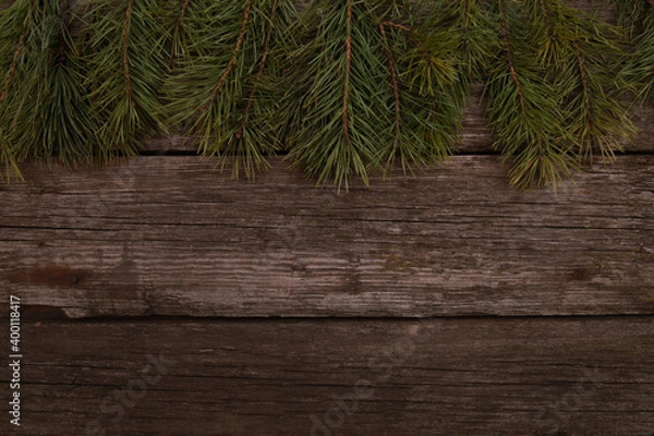 Fototapeta Christmas pine tree branches on old rustic wooden desk background. Xmas or New Year celebration concept. Top view, copy space, border, template for greeting cards and postcards