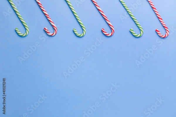 Fototapeta Five striped candy sticks lined up on a blue background. Christmas, New Year, holiday. Flat lay minimalism holiday concept. Copy space. 