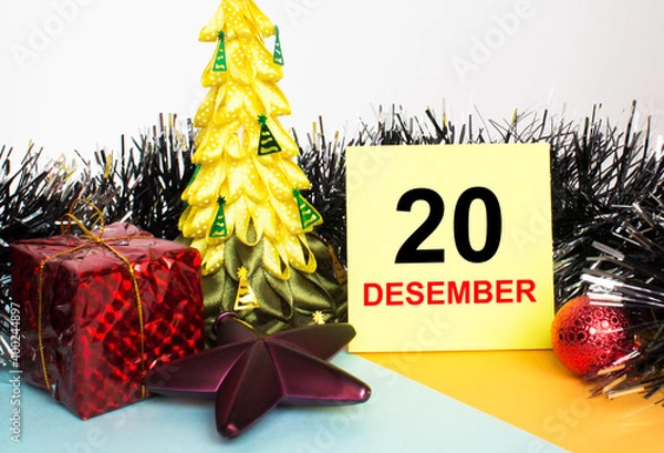 Fototapeta Christmas tree decorated with toys and tinsel, gift boxes and Yellow sticker with text 20 december