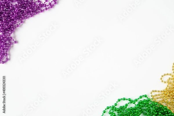 Fototapeta Mardi gras background, border on white with purple gold green beads and copy space