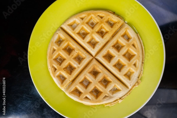 Fototapeta Fresh round waffle on a yellow plate from above