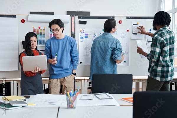 Fototapeta Group of university students is writing on a whiteboard and talking