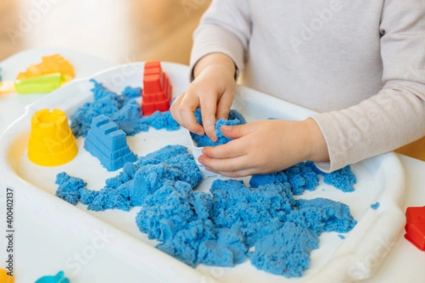 Fototapeta Close view of child's hands playing with kinetic sand. Children's creative game for early development and fine motor skills.