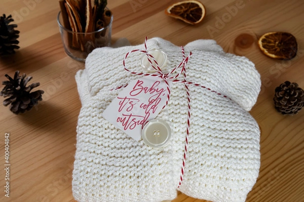 Fototapeta White woolen sweater wrapped as a gift, surrounded with dry orange slice and pinecone