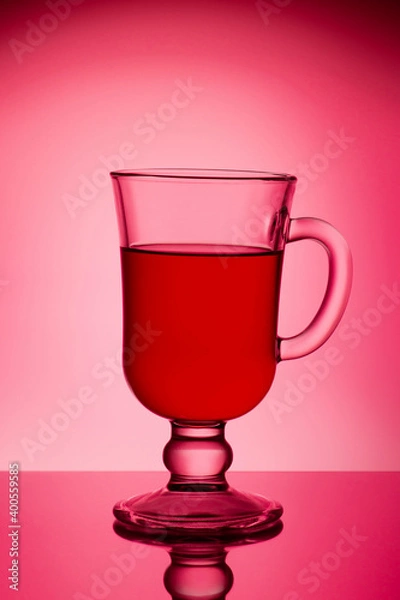 Fototapeta Glass with mulled wine on a red background. Glass for light.