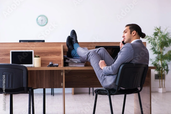 Fototapeta Young male employee working in the office