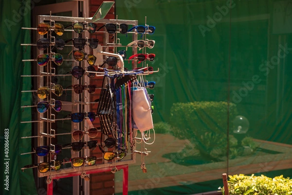 Fototapeta A booth offering sunglasses, now chinstraps or face masks have been added for tourists to shop due to the COVID-19 pandemic crisis