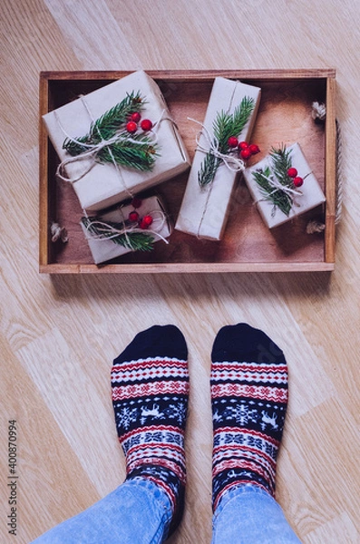 Obraz Feet with warm winter socks standing in front of Christmas gifts
