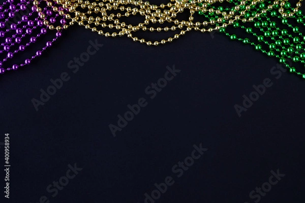 Fototapeta Mardi gras background on black with purple, yellow, green beads copy space