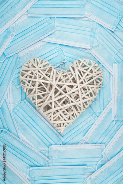 Fototapeta White heart on a background of a blue faces masks. Concept of a Valentines day during Coronavirus or Covid pandemic.