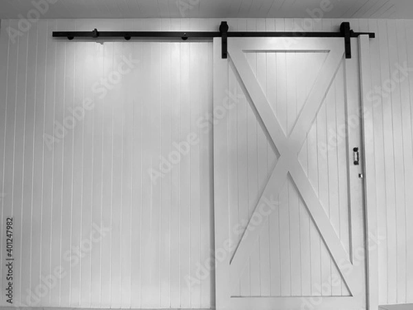 Obraz Large white sliding doors and black sliding rails against white walls.