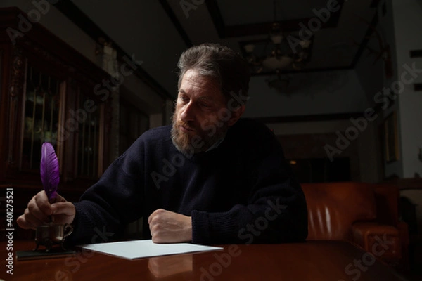 Fototapeta writer with beard writes on white sheet with goose feather
