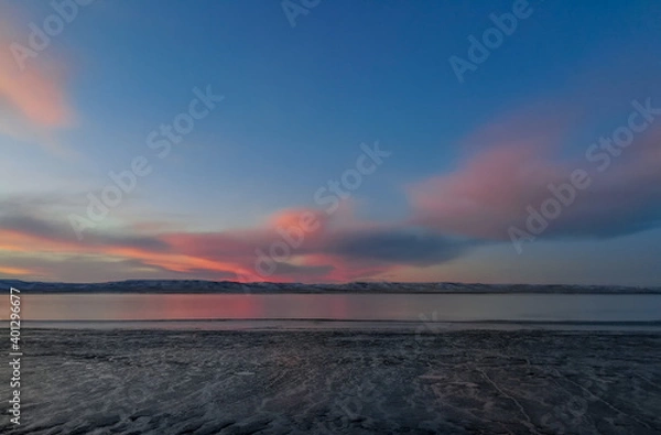 Fototapeta landscape of the estuary of the sky with pink clouds and cold tones, with the low tide of the water, aesthetic style, taken in the city of Rio Gallegos, Santa Cruz, Argentina, with space for text