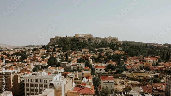 Fototapeta Aerial tilt up shot of Athens city buildings and Acropolis Architecture in background during sunny day in Athens,Greece.