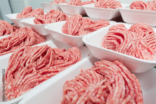 Obraz Minced beef flowing from meat grinder in butchery