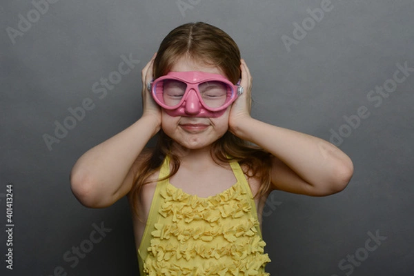 Fototapeta little girl in yellow swimsuit and pink mask. ear barotrauma