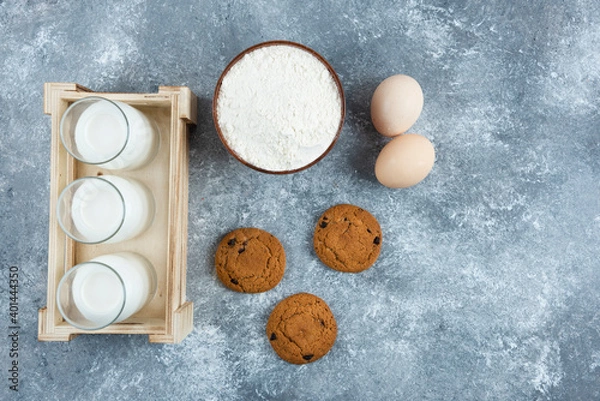 Fototapeta Three glasses of milk with flour and eggs on a gray background