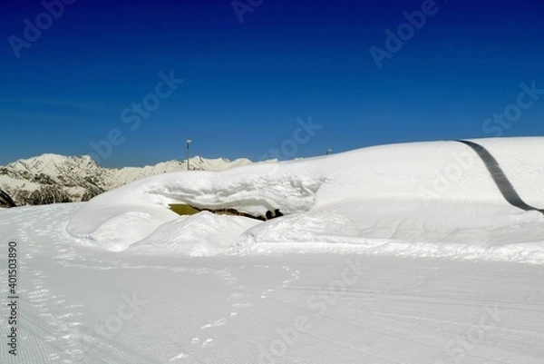 Fototapeta High snowdrifts against the background of fir trees and blue sky.