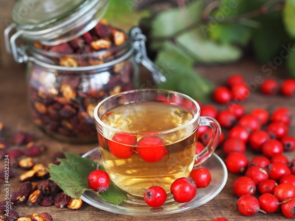 Fototapeta A cup of herbal healthy tea with hawthorn on a wooden background. Harvesting dried hawthorn for future use.Alternative medicine.