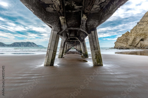 Fototapeta Wharf extending into the sea under a cloudy sky