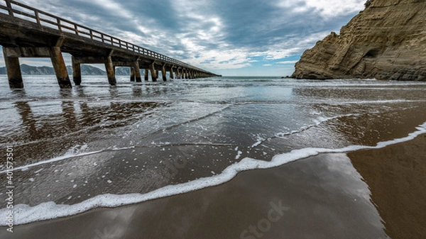 Fototapeta Wharf extending into the sea under a cloudy sky