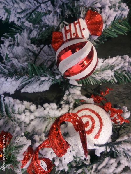 Fototapeta close up red and white christmas tree decorations on a snow covered tree